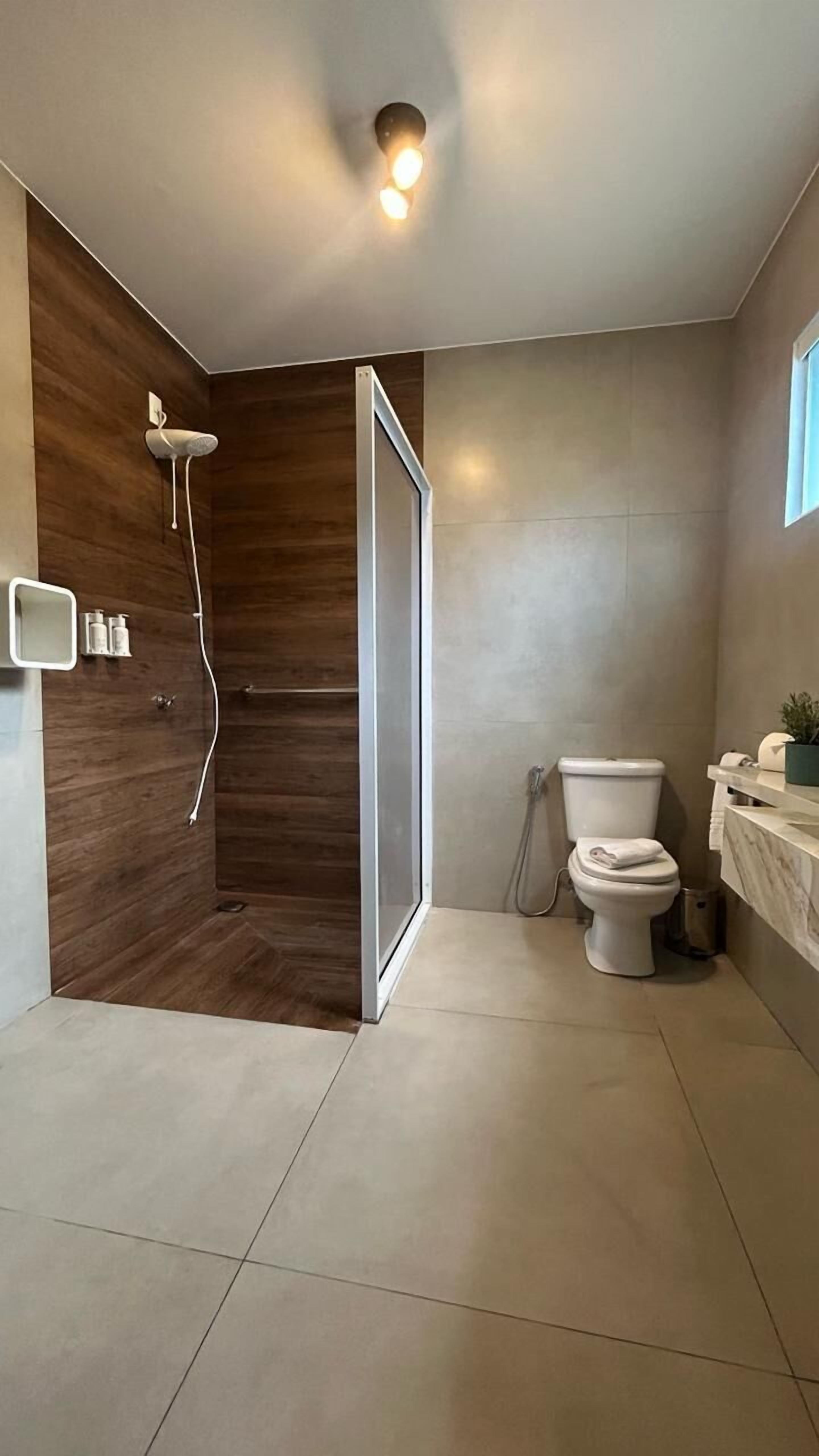 Een moderne badkamer met een douche, toilet en wastafel.