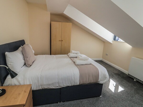 A bedroom with a bed, a nightstand, a wardrobe, and a skylight. - The Newborough Apartment 5 (Scarborough)