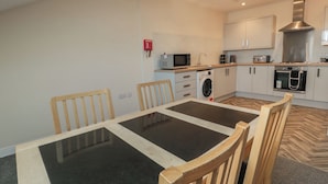 A modern kitchen with a built-in washing machine, microwave, and oven. - The Newborough Apartment 5 (Scarborough)