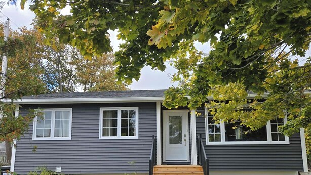 A two-story house with a front door, a small front porch, and a wooden staircase leading to the door.