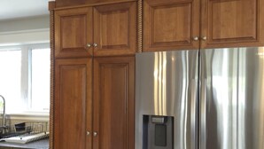 A kitchen with wooden cabinets and a stainless steel refrigerator.