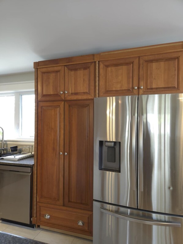 Cucina con mobili in legno e frigorifero in acciaio inossidabile.