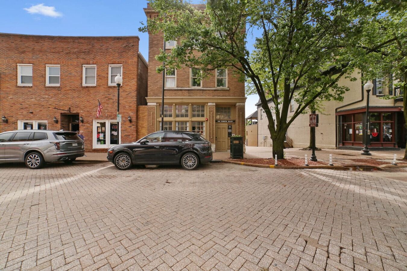 A brick building with a storefront, a tree, and a parked car.