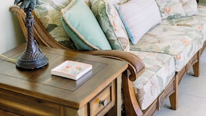 Une pièce chaleureuse avec un bureau en bois, une lampe, un canapé à motifs floraux et un tableau encadré au mur.