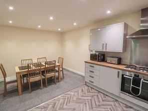 A compact kitchen with a dining table, chairs, a microwave, toaster, oven, and cabinets.