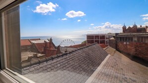A view through a window of a building with a tiled roof, a paved area, and a distant Ferris wheel. - The Newborough Apartment 4 (Scarborough)
