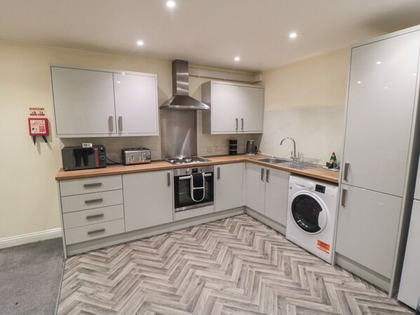 A modern kitchen with a microwave, toaster, stove, oven, sink, and washing machine.