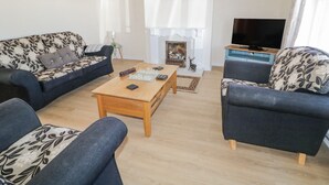 A living room with a fireplace, two sofas, a coffee table, and a television. - Hill House (Ballymoney)