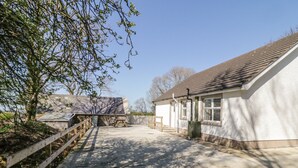 A building with a sloped roof, a wooden fence, and a paved pathway leading to it. - Hill House (Ballymoney)