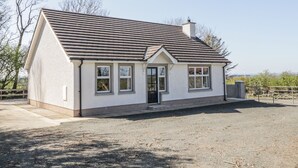 A single-story house with a gabled roof, a front door, and two windows on the ground floor. - Hill House (Ballymoney)