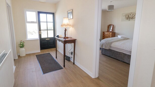 A bedroom with a bed, a dresser, a nightstand, a lamp, and a window. - Hill House (Ballymoney)