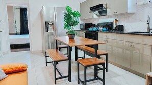 Una cocina moderna con una mesa de madera y bancos, un refrigerador, un microondas y un lavabo.