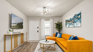 A modern living room with a sofa, a coffee table, a TV, and a painting.