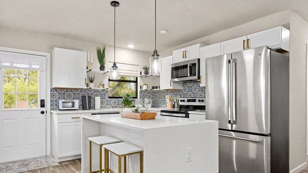 A modern kitchen with white cabinets, stainless steel appliances, and a central island with stools.