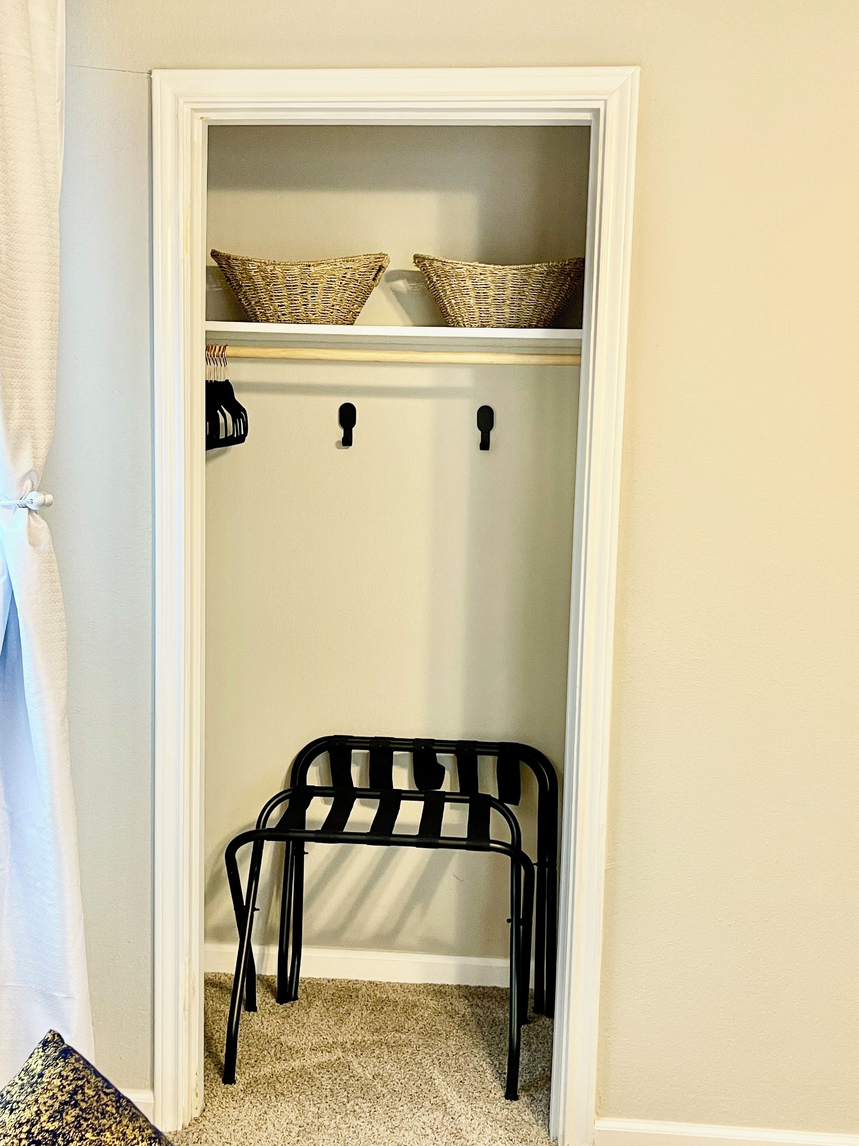 A closet with a hanging rod, a bench, and a shelf with baskets.