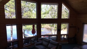 A cozy cabin with large windows offering views of a lake and forest. - Royal Lake Cabin (Royal Lake)
