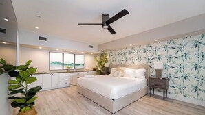 Ein modernes Schlafzimmer mit einem großen Bett, einem Deckenventilator, einem Nachttisch und einer Wand mit Bambusblattmuster.