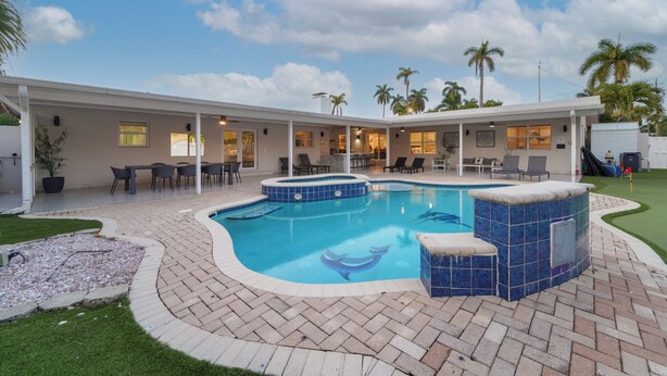 Ein Poolbereich mit Whirlpool, Liegestühlen und einer überdachten Terrasse.