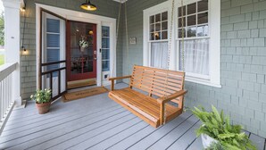 A porch with a wooden bench, a red door, and a white window with a curtain. - The Hansell House, your Downtown Thomasville Destination! Family + Pet Friendly! (Thomasville)