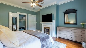 A bedroom with a bed, a ceiling fan, a fireplace, a dresser, and a television. - The Hansell House, your Downtown Thomasville Destination! Family + Pet Friendly! (Thomasville)