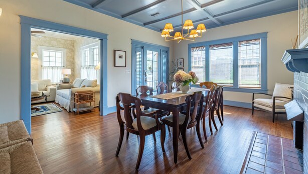 A dining area with a wooden table and chairs, a chandelier, and large windows with blue shutters. - The Hansell House, your Downtown Thomasville Destination! Family + Pet Friendly! (Thomasville)