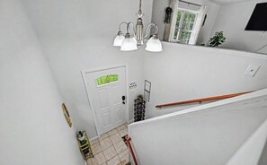 Una escalera con barandilla, una puerta con un letrero verde y un candelabro.