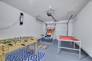 A room with a foosball table, a ping pong table, and a basketball hoop. - Spacious 4-bedroom house in Tobyhanna with game room, firepit (Tobyhanna)