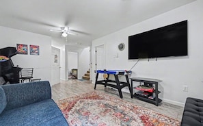 A living room with a sofa, a coffee table, a television mounted on the wall, and a patterned rug. - Spacious 4-bedroom house in Tobyhanna with game room, firepit (Tobyhanna)