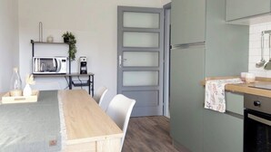A compact kitchen with a dining area, a microwave, a coffee maker, and a refrigerator. - QuickHome Appartamento Gelsomino (Andorno Micca)