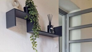 A modern living room with a grey sofa, a hanging plant, and a black shelf with decorative items. - QuickHome Appartamento Gelsomino (Andorno Micca)