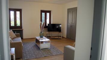 A living room with a sofa, a coffee table, a TV, and a door.