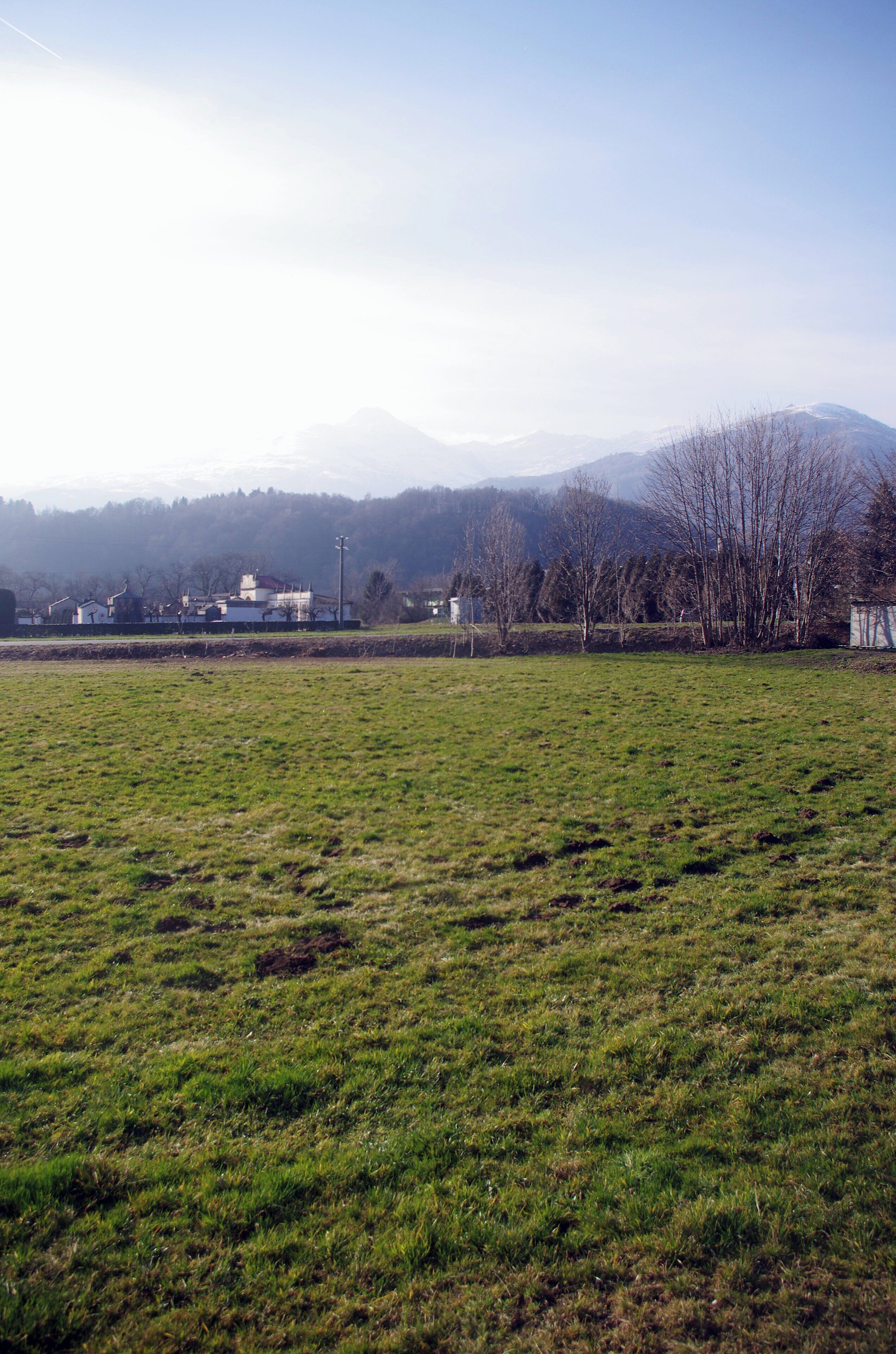 Un campo cubierto de hierba con vistas a edificios y montañas en la distancia.