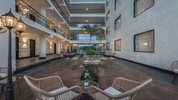 A spacious indoor area with multiple levels, wicker furniture, and a central plant.