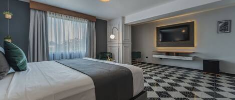 A modern hotel room with a large bed, a flat-screen TV mounted on the wall, a checkered floor, and a city view through the window.