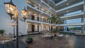 Ein mehrgeschossiges Atrium mit Außenbestuhlung, Geländern und Pflanzkübeln.