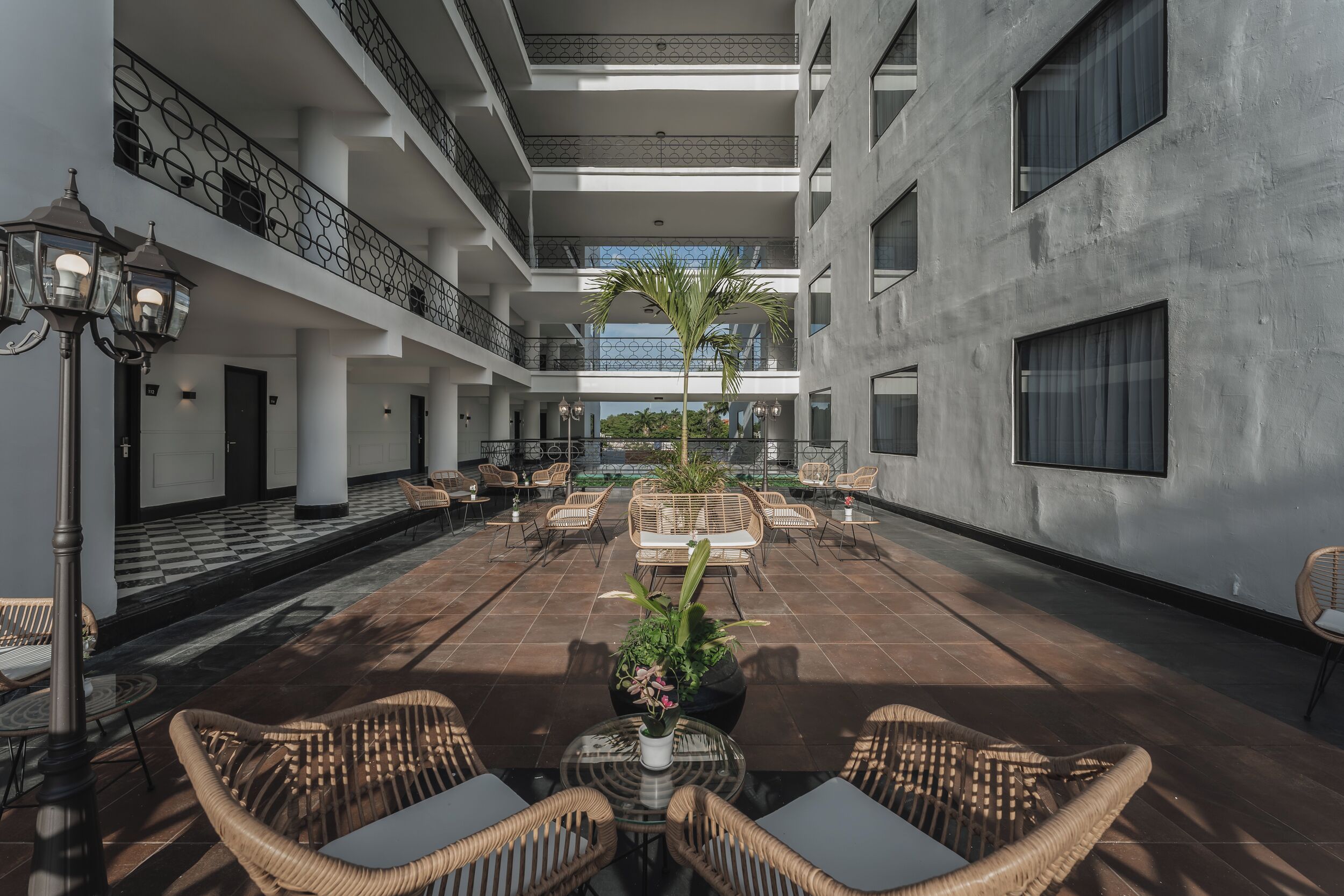 Un amplio patio interior con varias zonas de estar, una planta central y un diseño de suelo a cuadros.