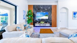 A spacious living room with a large flat-screen TV, a wooden coffee table, and a comfortable sofa. - Canal-Front Bright Escape 3+bed/2bath -Heated Pool-Family Fun! Pet friendly! (Cape Coral)
