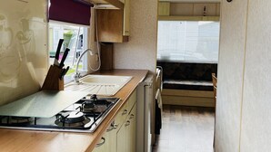 Une cuisine de taille réduite, dotée de meubles en bois, d’une cuisinière à gaz, d’un évier et d’un réfrigérateur compact.