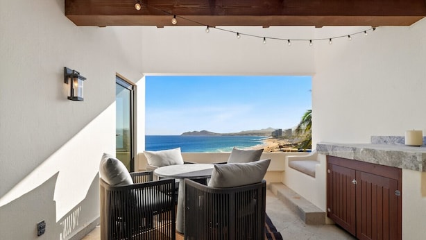 Un balcon avec vue sur la mer, un plafond en bois et une petite table avec des chaises.