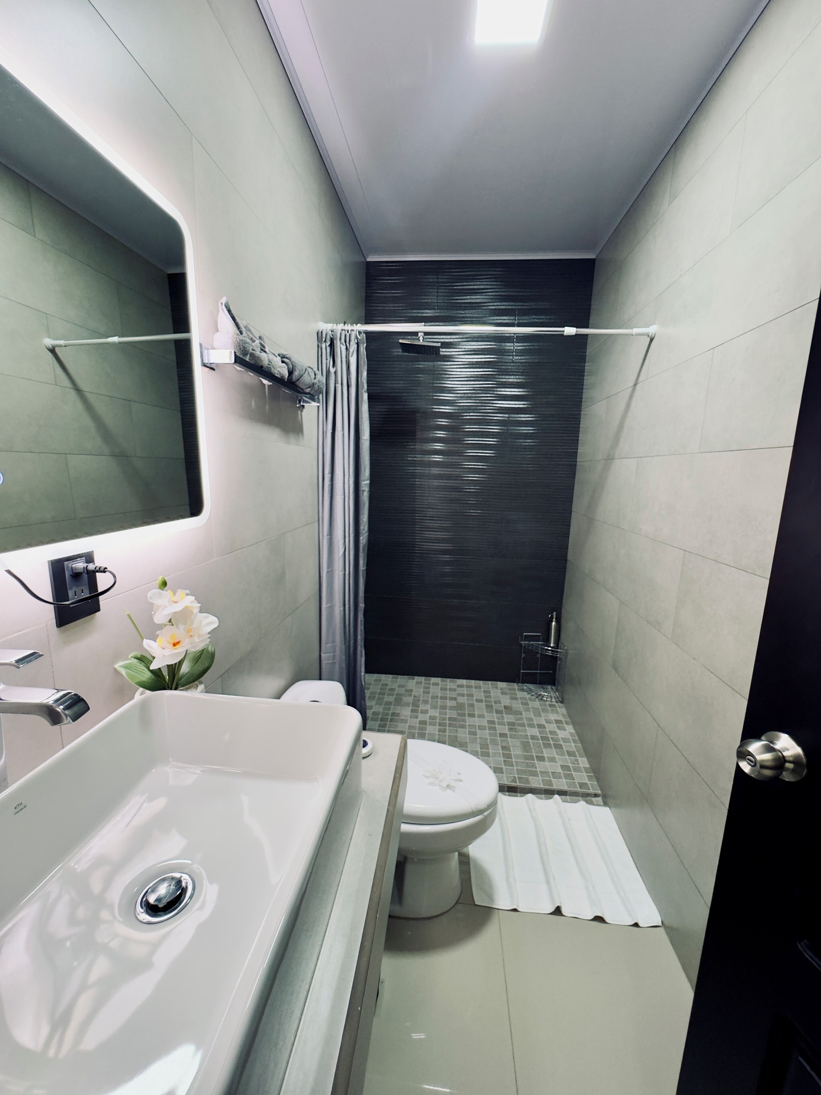 Ein modernes Badezimmer mit Waschbecken, Toilette und Duschbereich in Weiß.