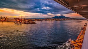 A waterfront cityscape with a prominent mountain in the background, a docked cruise ship, and a marina with boats. - Vacation Home Southern Geko (Torre del Greco)