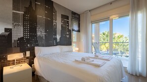 A modern hotel room with a large bed, a cityscape mural, a balcony with a view, and a white color scheme. - M Rmara in Javea X bia (Javea)