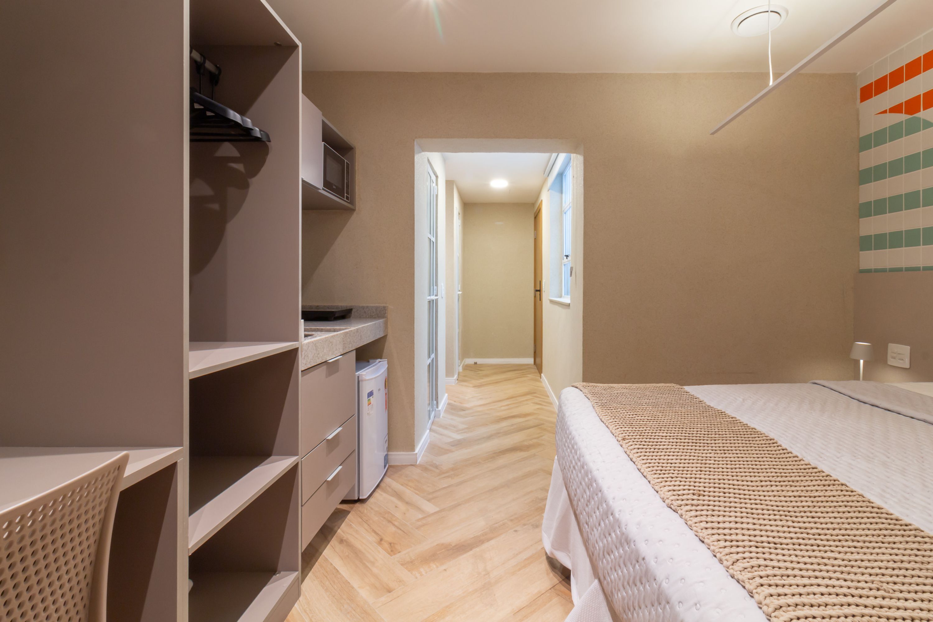 A bedroom with a bed, a wardrobe, a desk, and a chair.