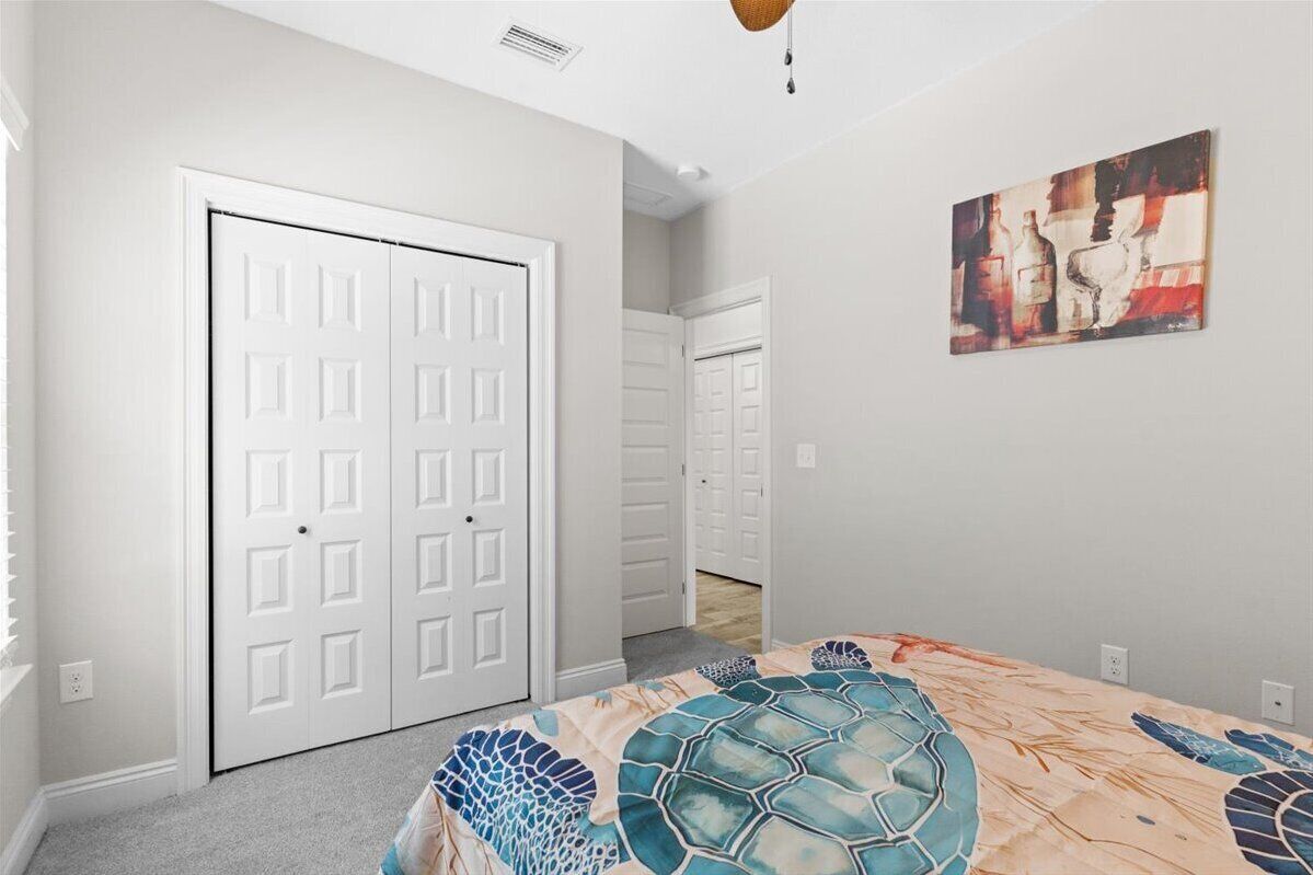 Une chambre à coucher avec un lit, une armoire blanche et un tableau accroché au mur.