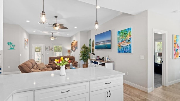 A spacious kitchen with a large island, pendant lighting, and artwork on the walls. - - August Deals - Beach Retreat with private Hot Tub & 5 min. to Navarre Beach (Navarre)