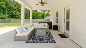 A covered patio with a sofa, a coffee table, and a ceiling fan. - - August Deals - Beach Retreat with private Hot Tub & 5 min. to Navarre Beach (Navarre)