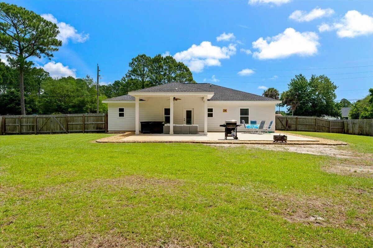 A single-story house with a covered patio, a lawn, and a wooden fence.