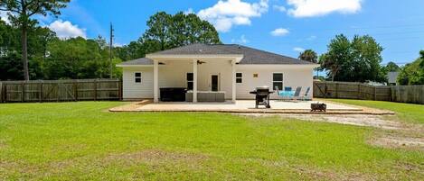 A single-story house with a covered patio, a lawn, and a wooden fence.