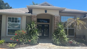 A house with a stone facade, a tiled roof, and a front entrance with a door and windows.