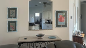 A dining area with a table, chairs, a bowl, and framed artwork on the wall.